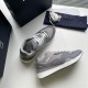 Top-down view of a pair of Dior grey trainers resting on a surface next to packaging in grey and white