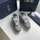 Pair of Dior grey low-top mesh trainers arranged alongside a dust bag and branded box in grey and white