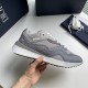 Hand showcasing the side profile of the grey leather and mesh Dior trainer in grey and white