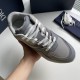 Hand holding a single Dior B29 grey trainer highlighting upper mesh texture and lacing in grey and white
