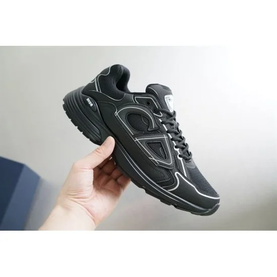 Hand holding Dior B30 black mesh trainer showing side profile and sole thickness