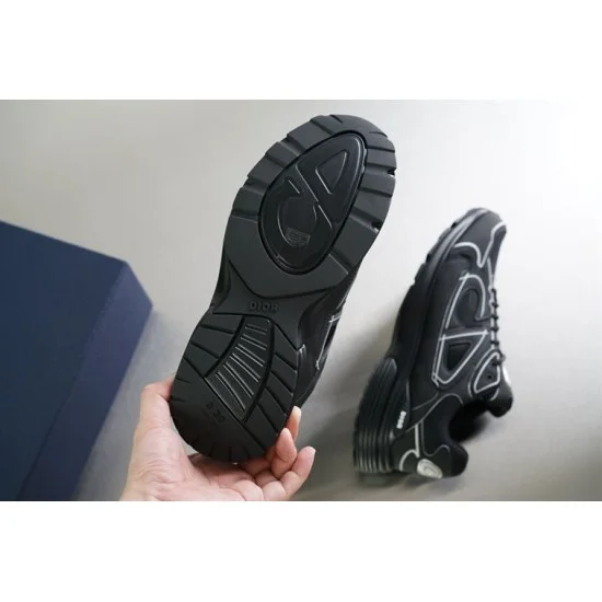 Hand holding the bottom tread pattern of black Dior B30 rubber outsole