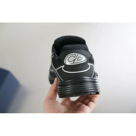 Rear heel view of Dior B30 black trainer held in hand showing CD logo emblem