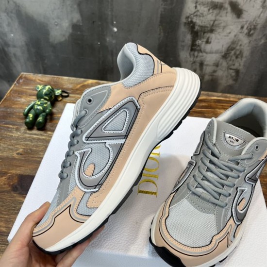 Hand holding Dior B30 grey and light pink trainer showing side profile