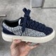 Hand holding Dior B33 navy blue oblique jacquard trainer showing side panel and thick laces