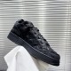 Dior B9S Black Quilted Leather Trainer Close Side Profile Elevated side view of single black Dior B9S quilted trainer held up against blind backdrop.