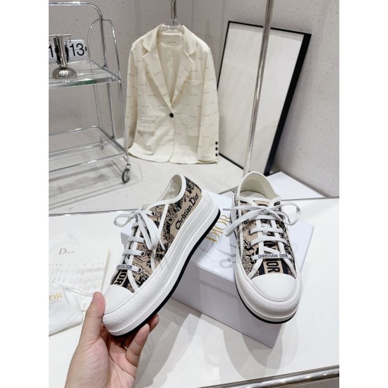 Hand holding a Dior Walk'n'dior platform trainer showing the side signature trim in beige