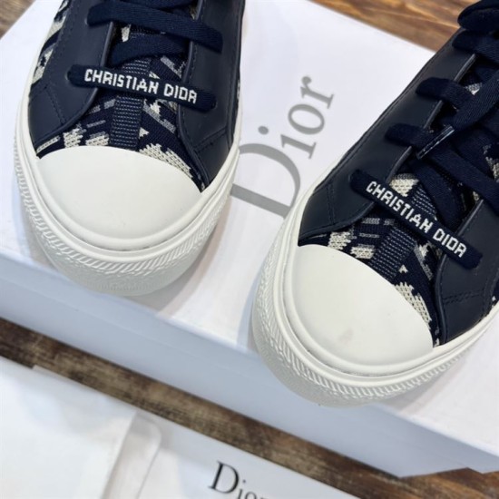 Close up of white toe caps and Christian Dior lace detailing on dark blue trainers