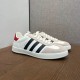 Pair of Gucci Gazelle White Leather Trainers in white and black Pair of Gucci Gazelle white leather trainers displayed on a wooden surface in white and black