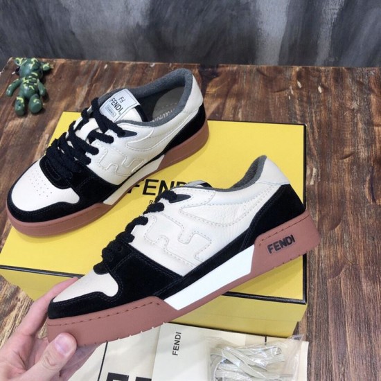 Hand holding a Fendi Match black and off-white suede trainer above packaging