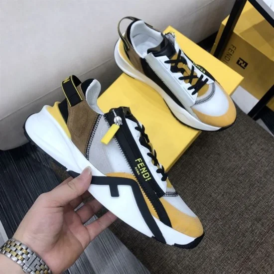 Hand holding a Fendi Flow trainer showcasing the lateral zip and yellow suede toe panel in multicolour and white
