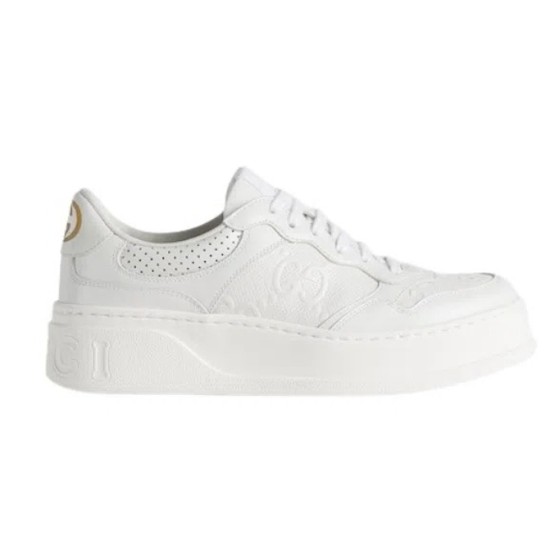 Profile view of Gucci white leather low-top trainer featuring embossed monogram and thick rubber sole