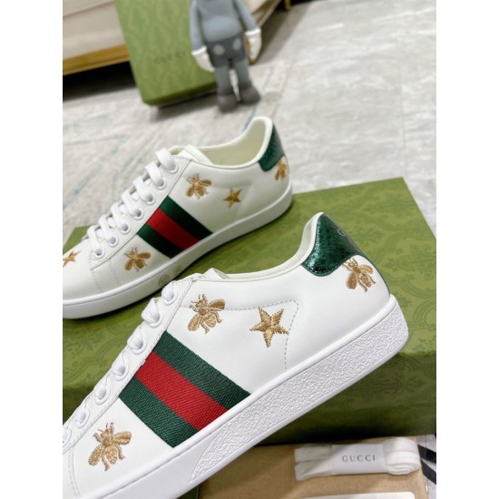 Close-up view of gold bee embroidery and Web stripe on white leather trainers