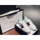 Pair of white Gucci Ace x Disney trainers next to luxury shopping bag