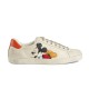 Gucci Ace Disney Mickey Mouse Ivory Leather Trainer Lateral View in ivory and orange Side profile of Gucci Ace Disney Mickey Mouse ivory leather trainer featuring a Mickey Mouse graphic and orange heel tab