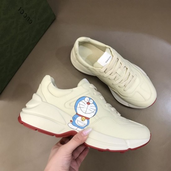Gucci Rhyton Ivory Trainers Dynamic Angle in ivory and red Gucci Rhyton trainer pair shown in dynamic arrangement highlighting leather finish and graphics in ivory and red