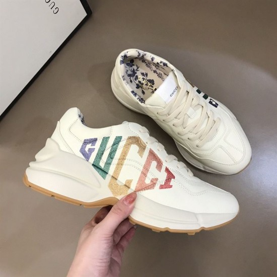 Gucci Rhyton Trainer Handheld Lateral View in ivory Handheld side profile of Gucci Rhyton ivory trainer showing glitter logo