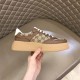 Gucci GG Supreme Brown Platform Trainer Hand View in brown and white Hand holding side of Gucci GG Supreme brown leather platform trainer against quilted background in brown and white