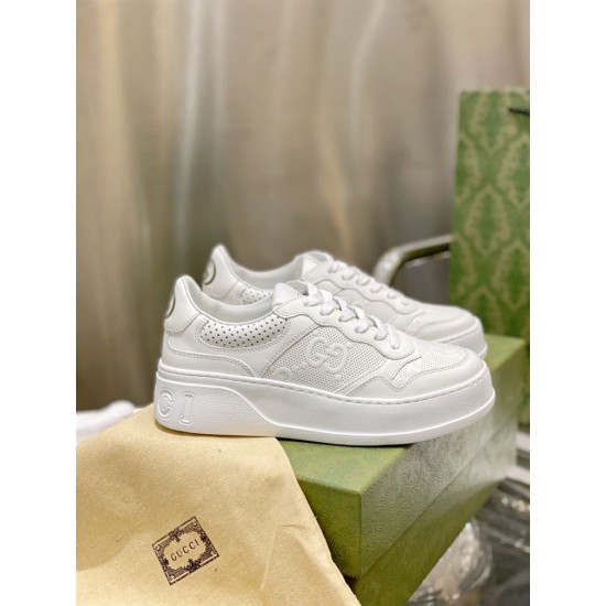 Gucci White Leather Low Tops Side View Side profile of Gucci white embossed leather trainers set on green shoe box