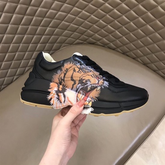 Gucci Rhyton Tiger Print Leather Trainer Outer Lateral View in black Hand holding single Gucci Rhyton black trainer showing outer tiger motif