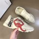 Gucci Rhyton Trainer Handheld Lateral View in off white Off white Gucci Rhyton trainer held in hand showing side graphic print