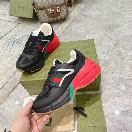 Gucci Rhyton Black Trainer Held in Hand in black and red Hand holding single Gucci Rhyton trainer showcasing red sculpted midsole and green side accent in black and red