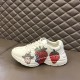 Gucci Rhyton Strawberry Print Side View in ivory and red Gucci Rhyton ivory trainer placed on leather surface highlighting outer print in ivory and red