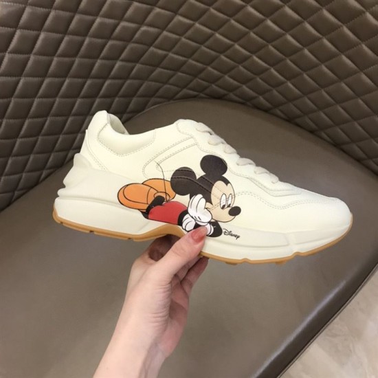 Gucci x Disney Rhyton Trainer Lateral Profile in ivory Hand holding Gucci x Disney Rhyton trainer displaying lateral graphic in ivory