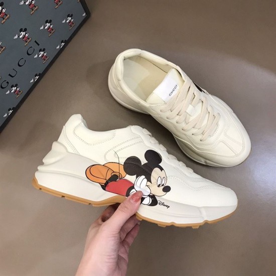 Gucci x Disney Rhyton Trainer Angled View in ivory Angled view of Gucci x Disney Rhyton trainer held in hand in ivory