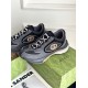 Angled front shot of grey and black Gucci trainers with patterned laces