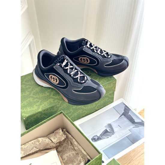 Pair of Gucci grey and black trainers resting on green patterned shoe box