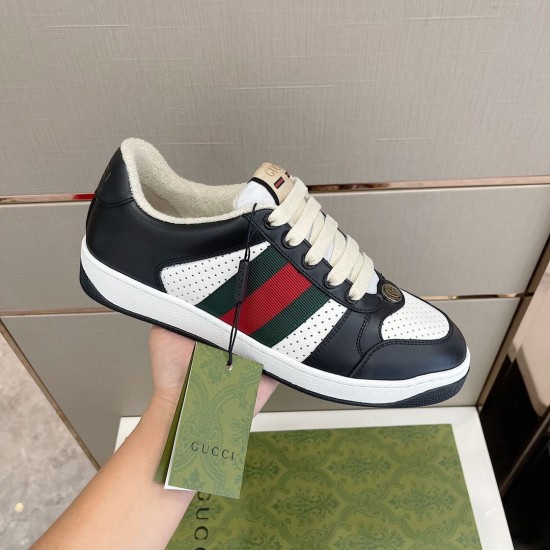Handheld view of Gucci Screener black and white trainer displaying branded green tag