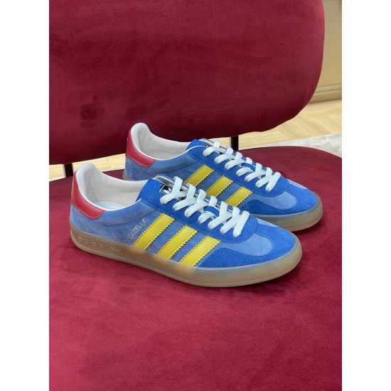 Pair of Gucci Gazelle Blue Suede Trainers in blue and yellow Pair of Gucci Gazelle blue suede trainers resting on red surface in blue and yellow