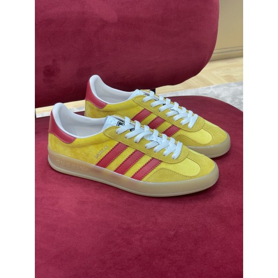 Pair of Gucci yellow and red velvet trainers resting on red surface