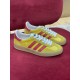 Pair of Gucci yellow and red velvet trainers resting on red surface