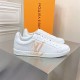 L classic white leather trainers with gold motif accent on display table L classic white leather trainers with gold motif accent displayed on a metallic surface