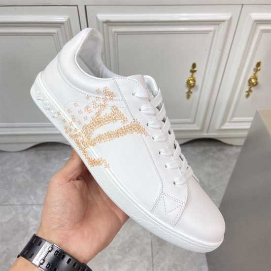 L classic white leather trainers with gold motif accent outer profile L classic white leather trainers with gold motif accent held up displaying the outer side