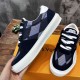 L Ollie Richelieu Navy Blue Low Top Trainers - Handheld Side View L Ollie Richelieu navy blue trainer held up to show the side and upper