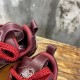 Close-up of the padded collar and heel pull tabs on burgundy trainers in burgundy and white