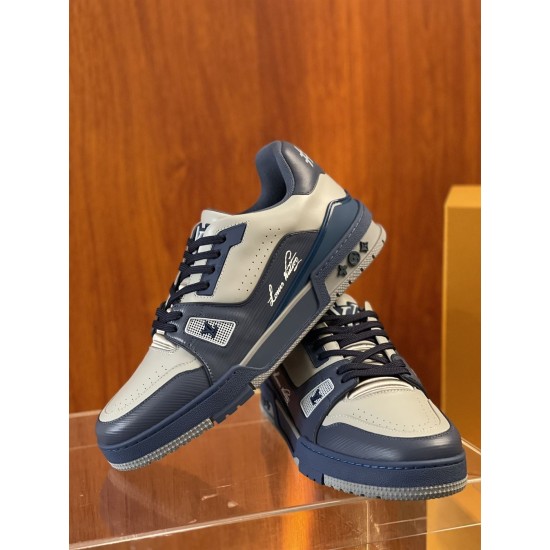 Front three-quarter view of L Trainer grey and navy blue leather sneakers resting on display stand