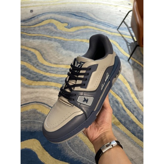 Handheld angle view of L Trainer grey and navy blue leather sneakers showcasing toe perforations