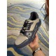 Handheld angle view of L Trainer grey and navy blue leather sneakers showcasing toe perforations