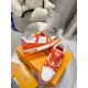 Pair of L Trainer Low Top Orange And White Leather Sneakers arranged on display box