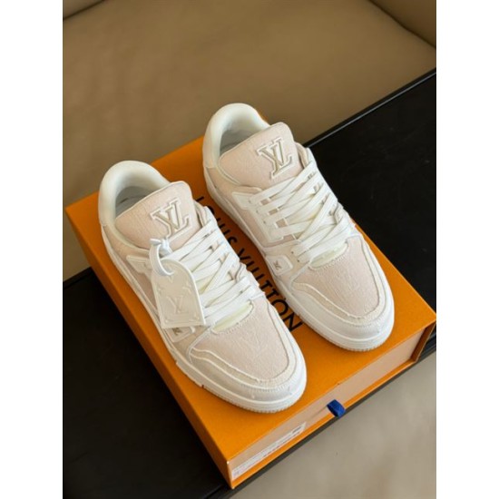 L Beige Trainers Top Angle View in beige and white Top angle view of L beige trainers resting on an orange branded box in beige and white