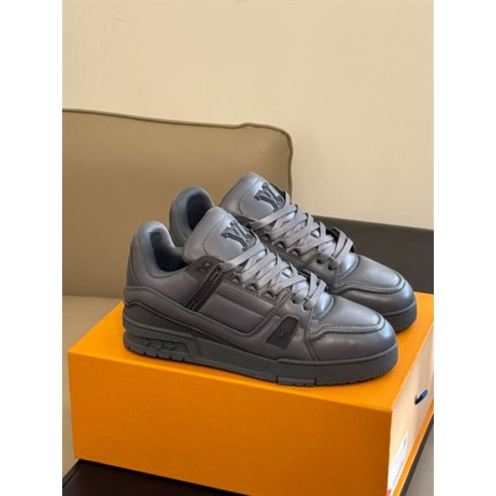 Pair of grey L trainers resting on an orange box in interior lighting in monochrome and grey
