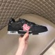 Lateral outer side of L black monogram leather trainer low top shoes held in hand in black and red