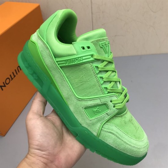L green monogram denim trainers held up Hand holding the L green monogram denim trainers to show upper construction