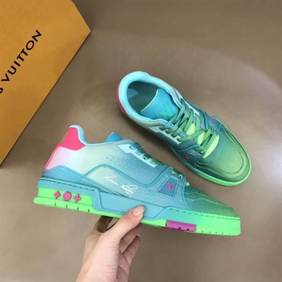 L Trainer Low Top Sneakers In Green Grained Leather - Overhead Angle in green and pink Top angle view of L trainer low top sneakers in green grained leather held against a quilted background in green and pink