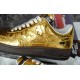 Close-up profile of metallic gold trainer showing side Swoosh and stitching