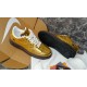 Angled view showing upper pattern and dark sole tread of gold Nike trainer